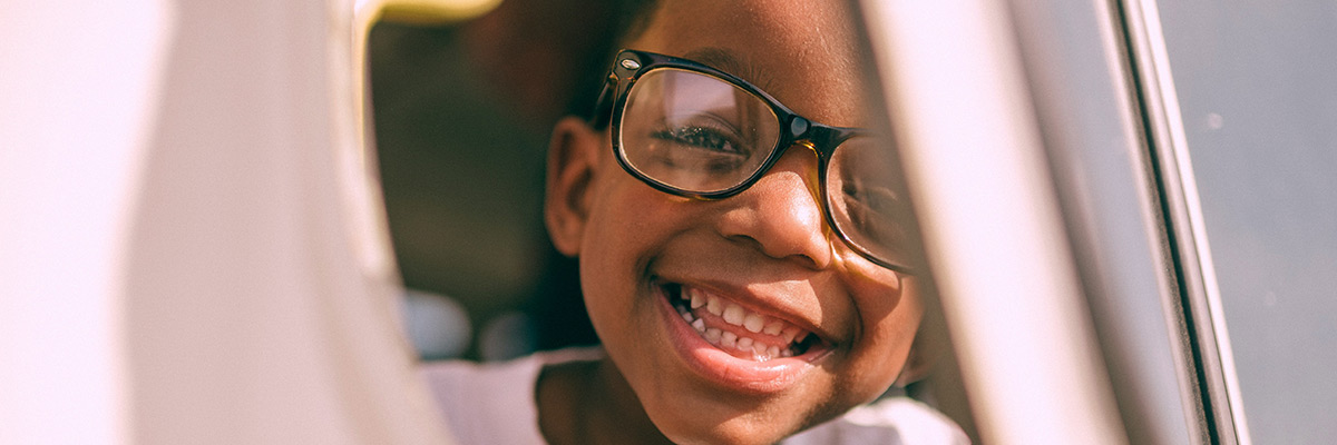 Close up of a boy with glasses smiling into the camera