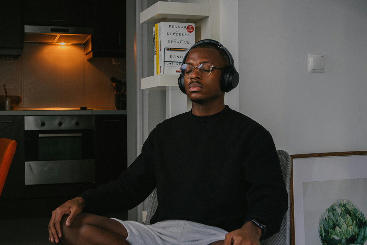 A man sitting with headphones taking a deep breath
