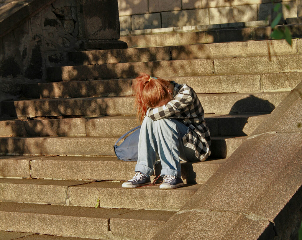 Teen sitting on steps in their head down