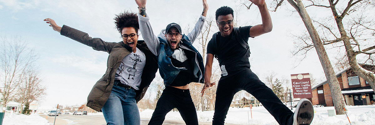 three teenagers jumping on the sidewalk