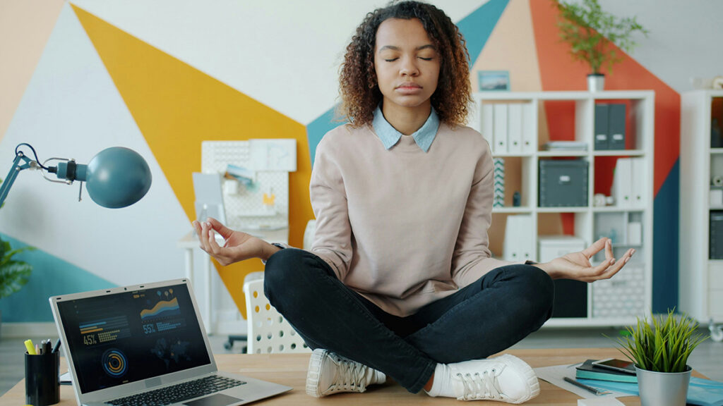 African American girl balancing on a desk while meditating